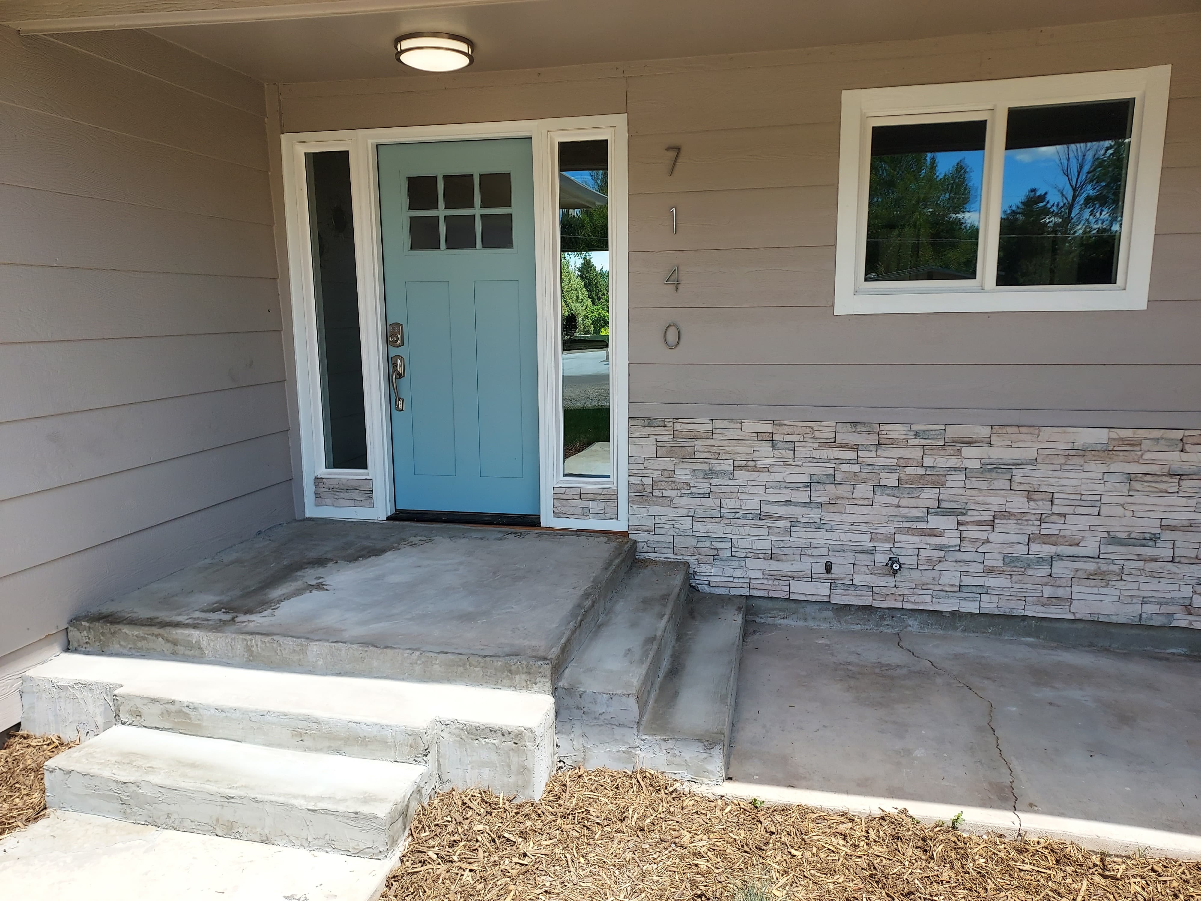 CLose up of a tan house with a teal door