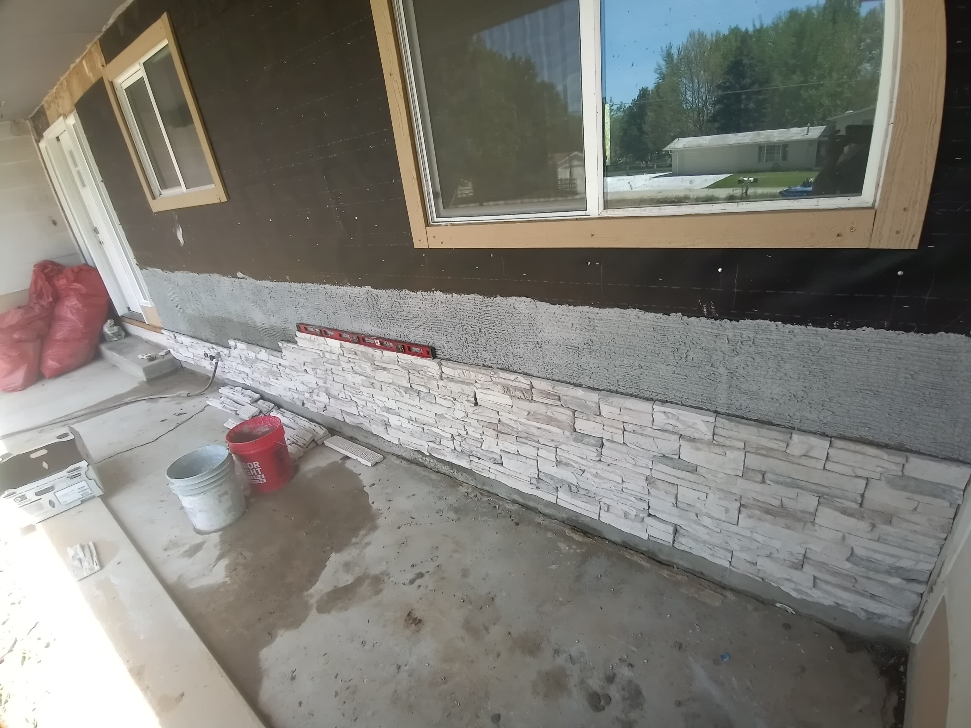 Tan house with stone being installed on the lower part of the outer walls