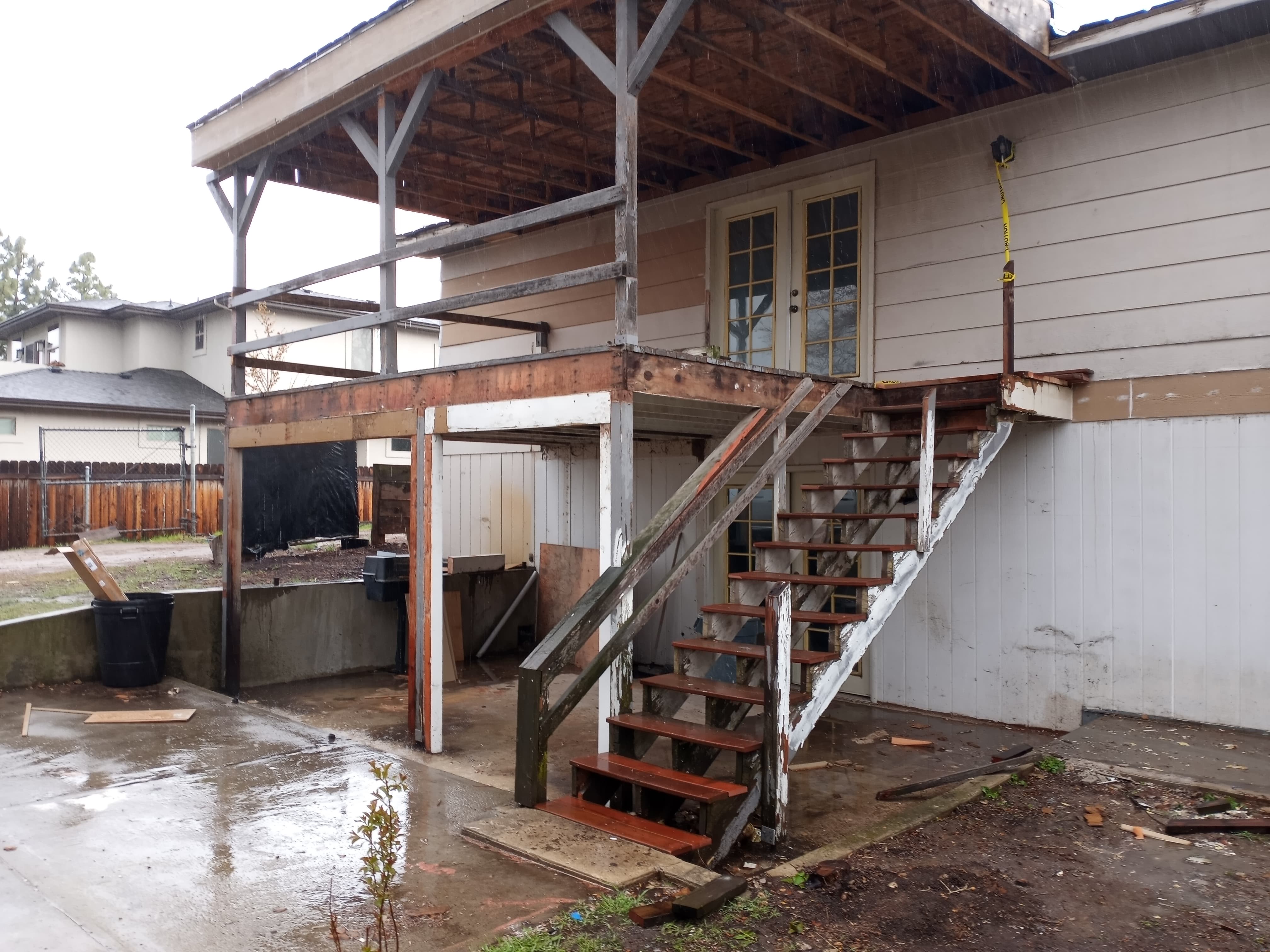 Two story house with a back patio and rotted stairs