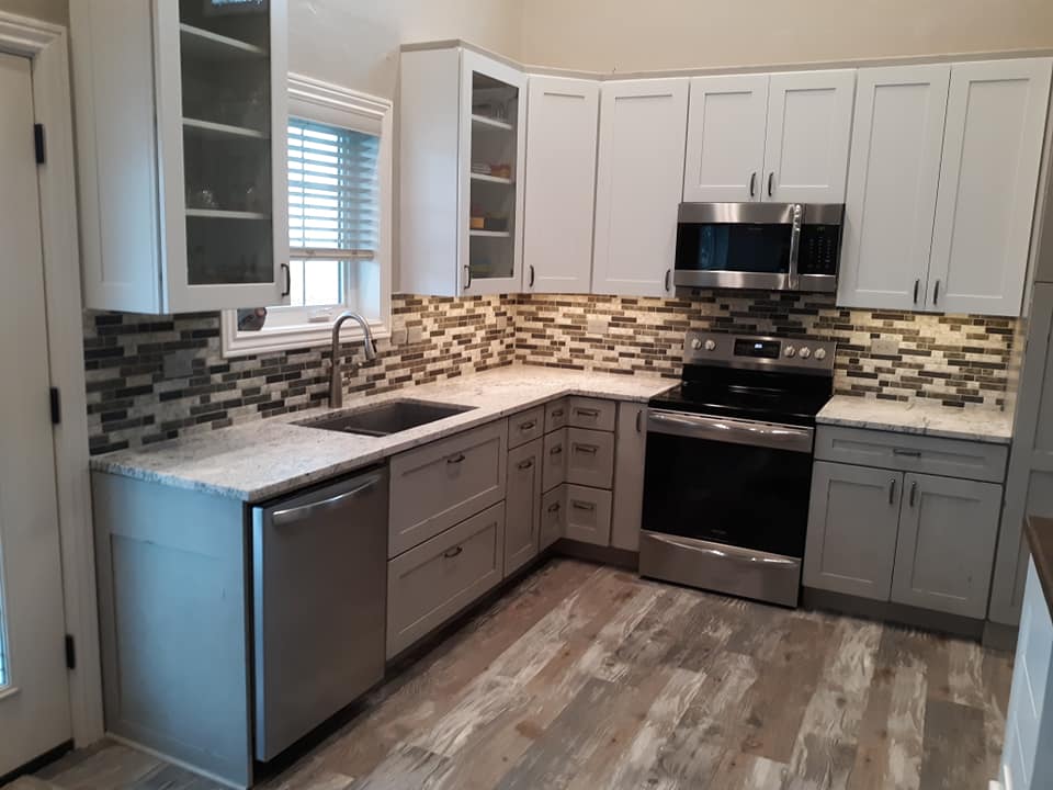 Kitchen with white cabinets and brown and white backsplash
