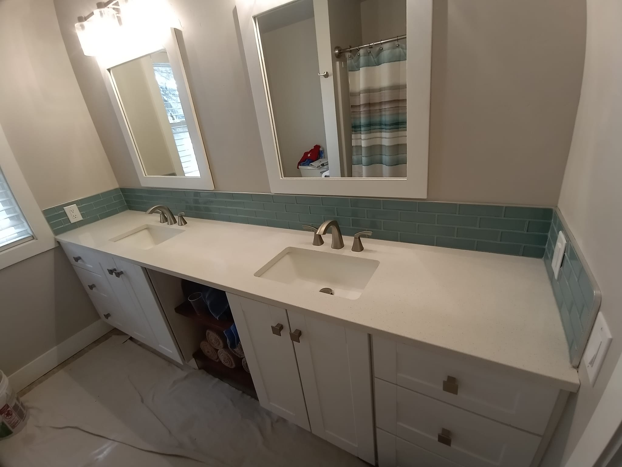 Bathroom vanity with white cabinets and teal backsplash