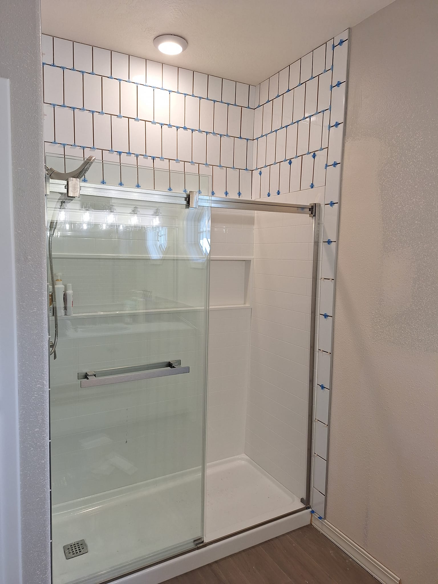 Bathroom shower with brand new white tile and glass door