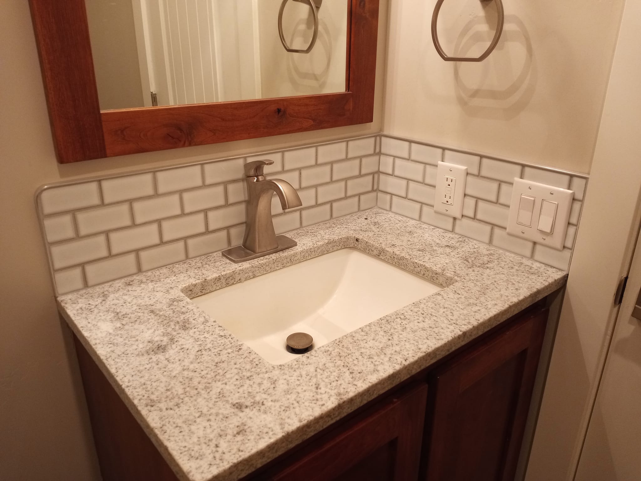 Cherry wood bathroom vanity with white subway tile backsplash