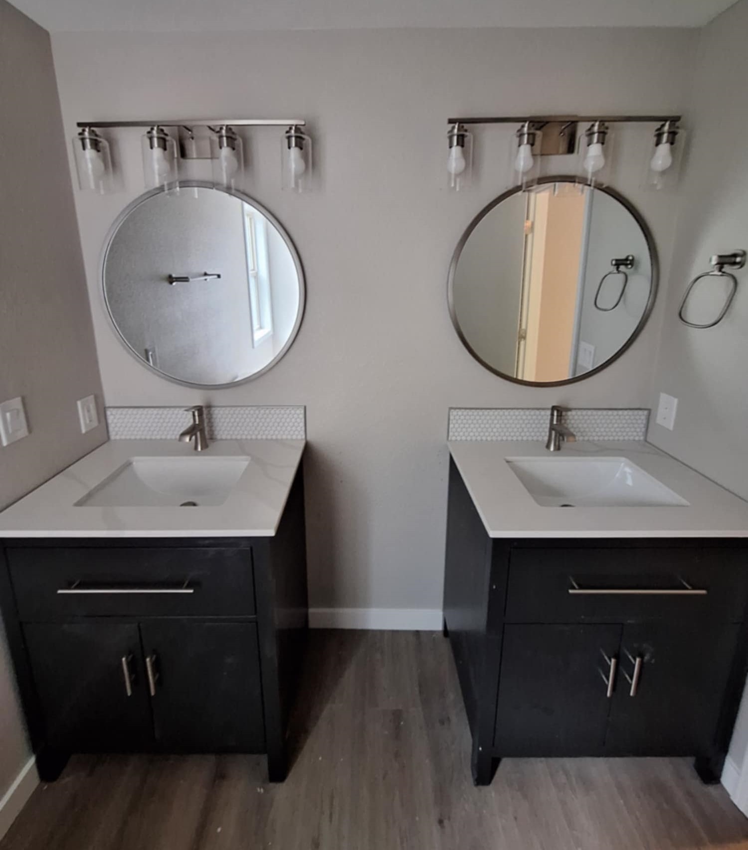 Dual bathroom vanities with espresso cabinets, round mirrors, and 2 vanity lights