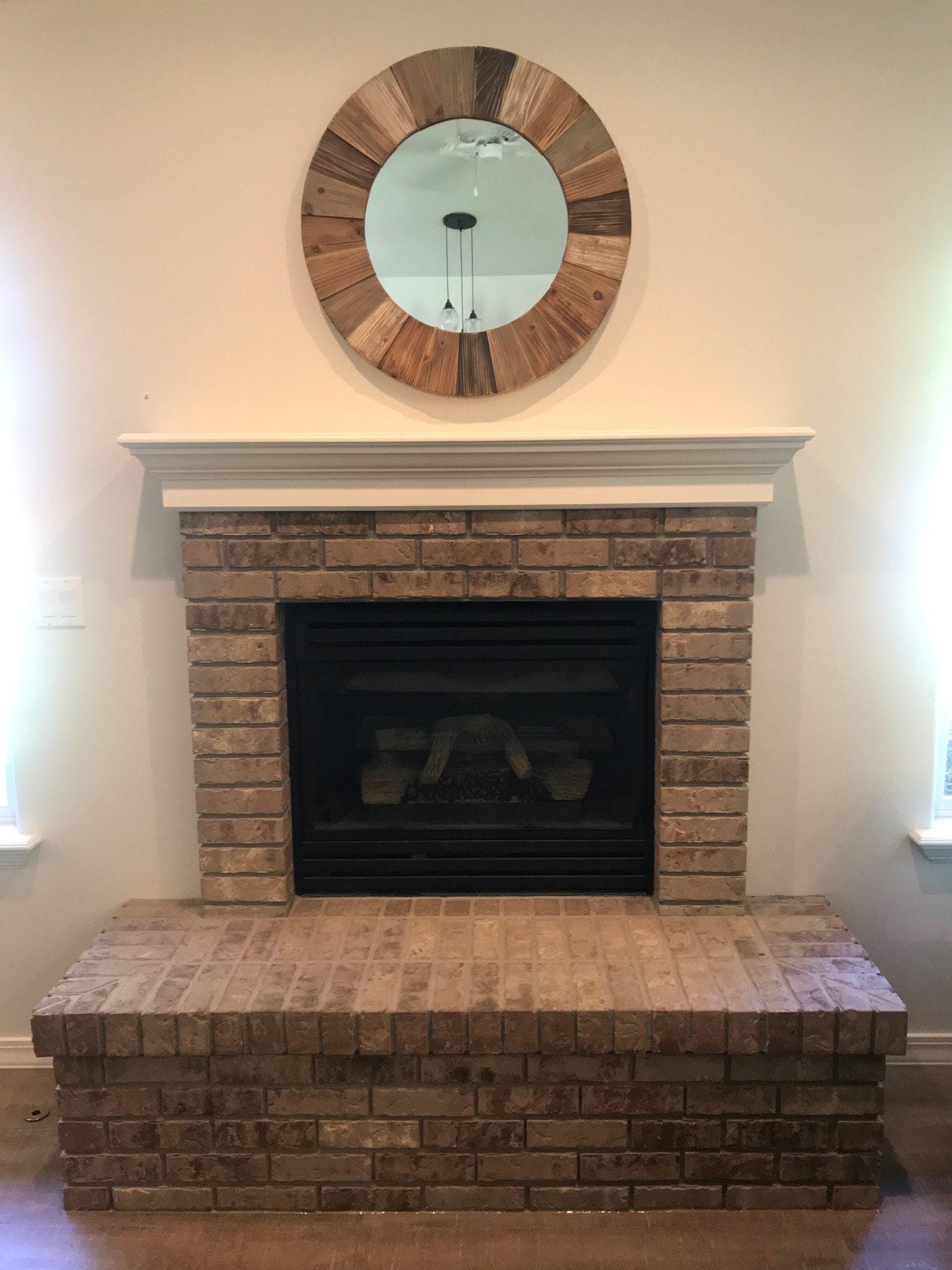 Red brick fireplace with round mirror above