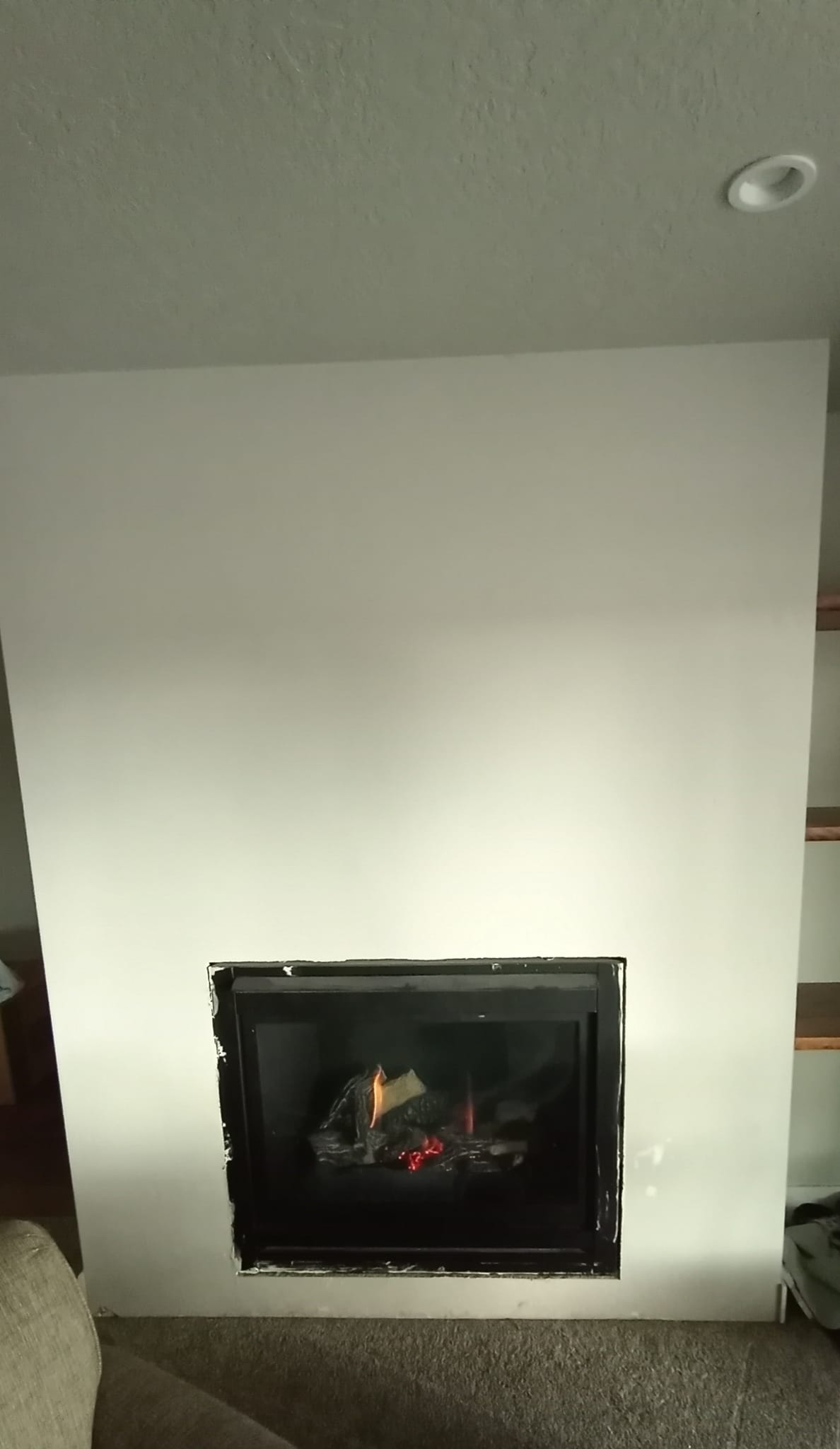 Progress of a fireplace being installed inside a blank wall