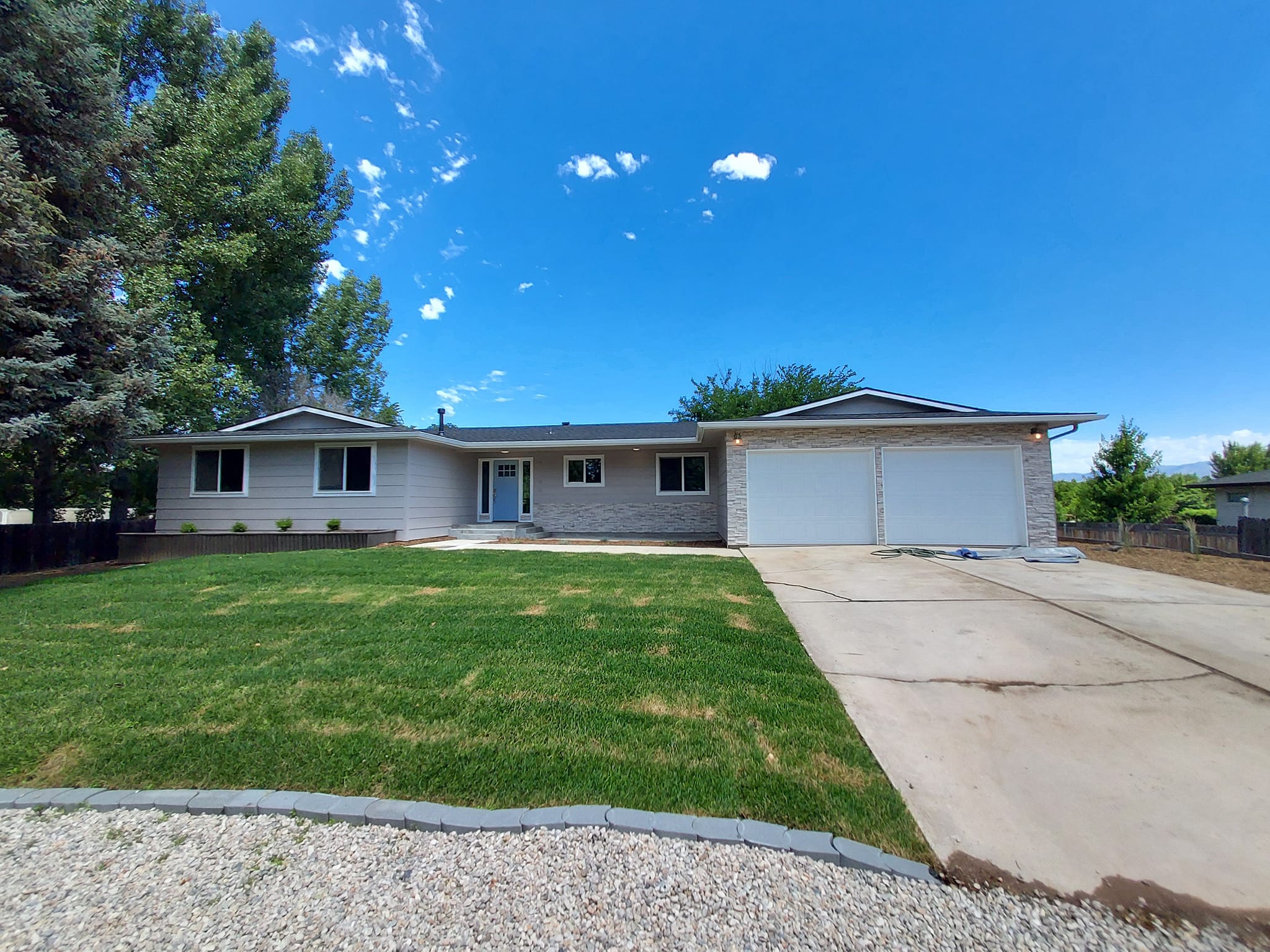 White house with 2 car garage and bright blue sky