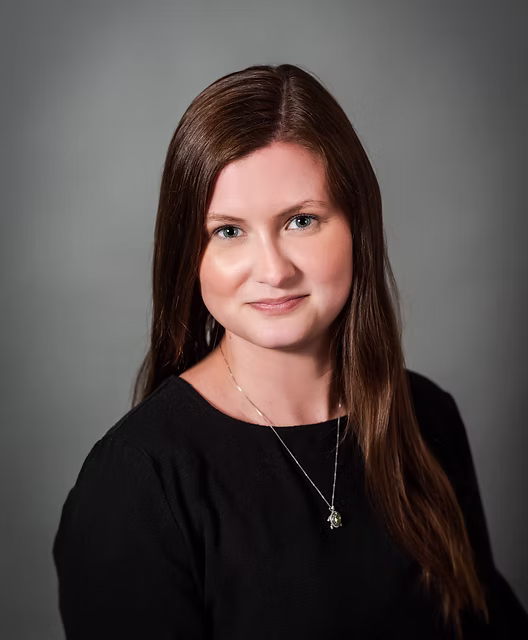 Candace, instructor at Dancing for Joy, with long straight brown hair and a gentle smile against a soft gray background