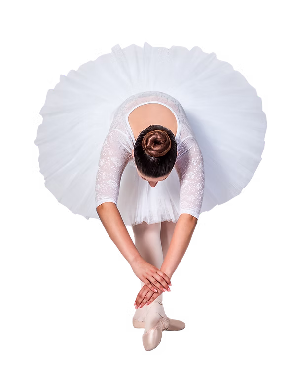 A ballet dancer in a white tutu is photographed from above as she bends forward gracefully, hands clasped over her pointe shoes in a classical pose.