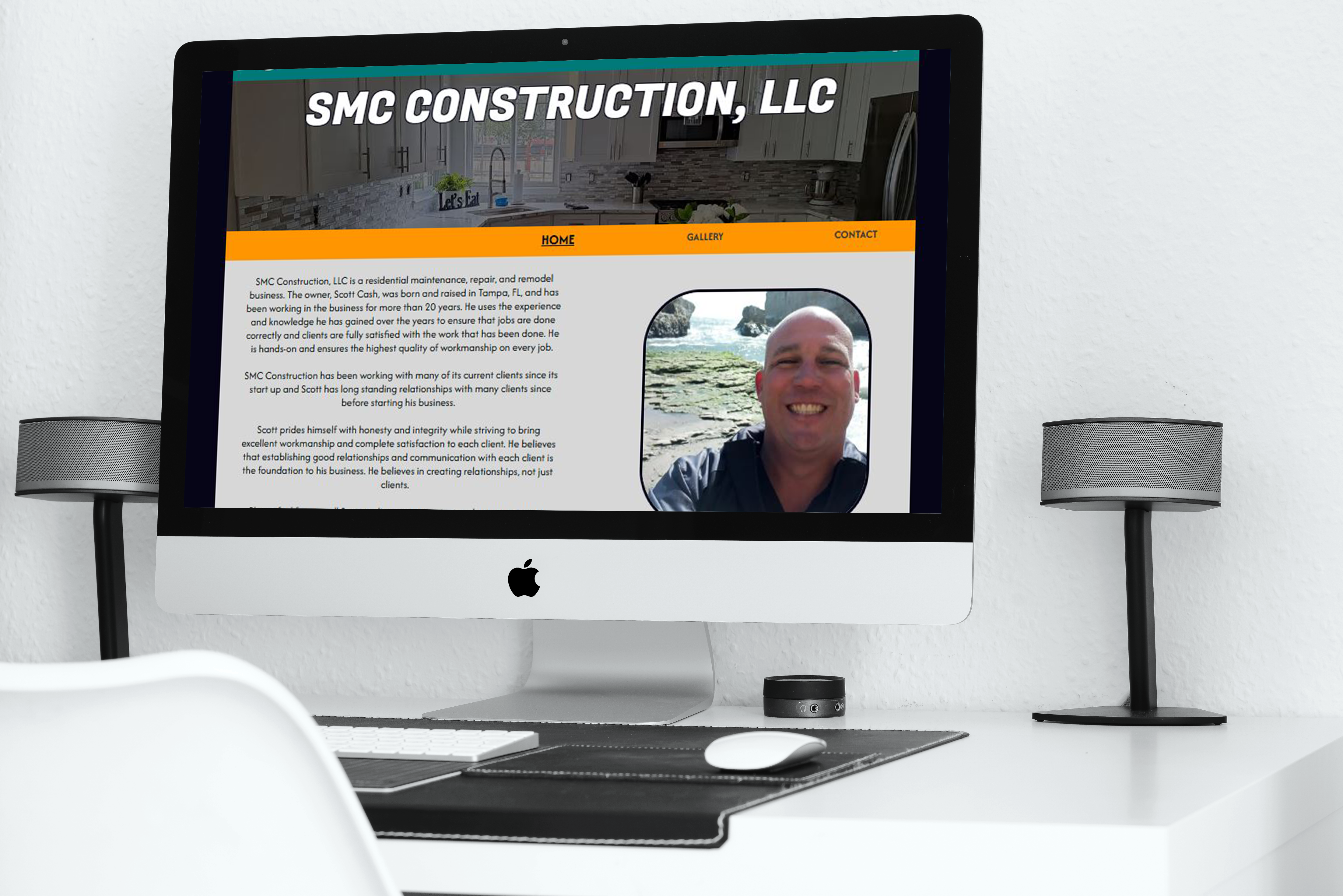 An iMac on a clean white desk displays the SMC Construction website, featuring the company header, navigation menu, business description, and a photo of the owner beside the text.