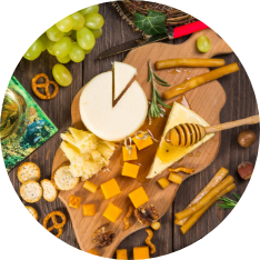 A wooden serving platter with cheeses and honey