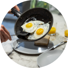 Person is serving sunny side up eggs from a pan